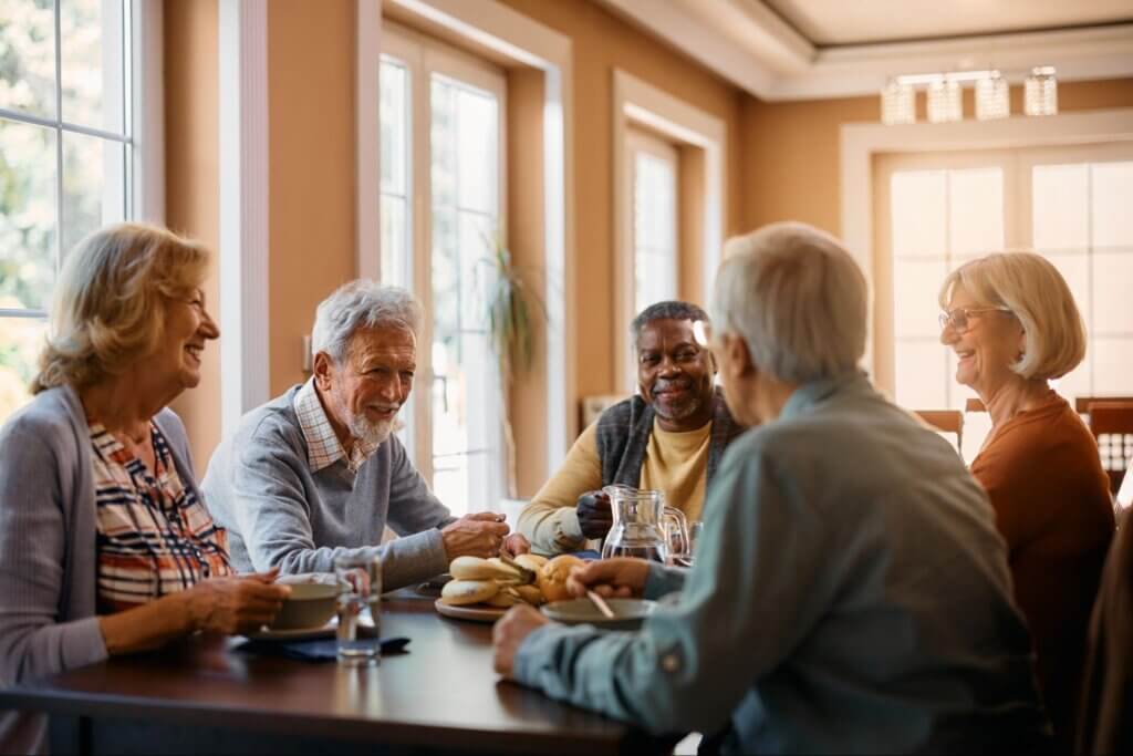 Happy seniors talking while eating lunch at senior care home